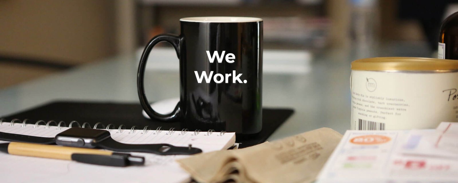 A mug reading "We Work." on a desk